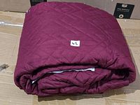 Folded burgundy quilted slipcover showing overall size