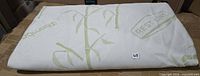 Folded white bamboo-pattern mattress protector on table