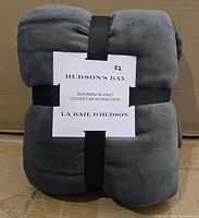 Rolled grey blanket with Hudson’s Bay card and black straps