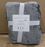 Front view of folded grey blanket with label