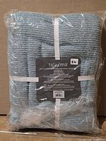 Package showing folded blue bath sheets in plastic wrap