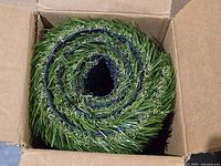 Rolled synthetic grass turf inside open shipping box