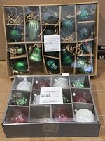 Two boxes of Gluckstein Home ornaments, one green set, one mixed colours