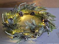 Top view of wreath showing frosted greenery, pinecones and LED lights