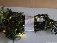 Garland close-up showing branches, lit LEDs, tag, battery box