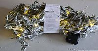 Full view of snow-flocked LED garland with tag and battery box