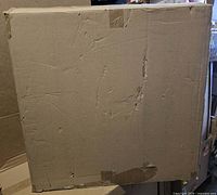 Sealed plain cardboard shipping box containing lounger