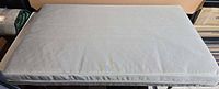 Full view of light grey crib mattress