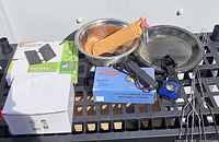 All items displayed on shelf including rope, bowls, pans, boxed lantern and waffle iron, headlamp, lighter, forks