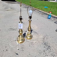 Two brass table lamps side by side on driveway