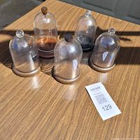 five small clear domes on wood bases grouped on tabletop