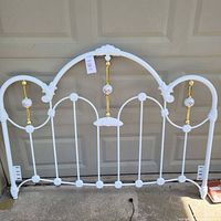 Full front view of white iron headboard with brass and porcelain details