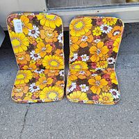 Two floral cushions standing upright on pavement