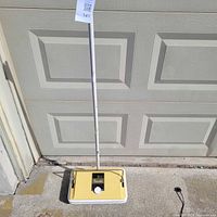 Full view of upright carpet sweeper against garage door