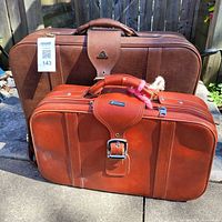 Front view of both suitcases displaying color, size and hardware
