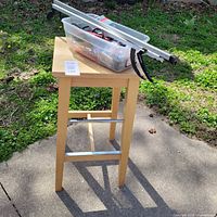 Full view of wood bar stool with bin of cords and aluminum rails on top