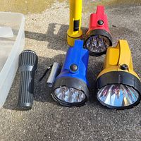 Group of seven flashlights on ground showing colors and styles