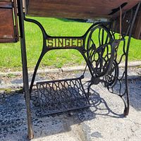 Side view of wrought iron base with SINGER lettering and treadle pedal