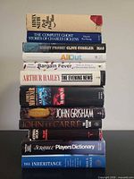 Stack of thirteen books showing spines for author and title identification