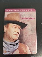 Front of metal tin showing John Wayne portrait, title and 20 westerns on 4 DVDs banner