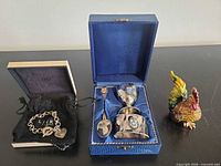 Overview of bracelet in pouch and box, blue cased baby set, and jeweled rooster