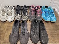 Six pairs men’s athletic shoes arranged on floor showing styles, colors and wear