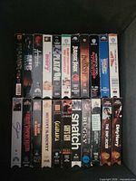 Box showing two rows of VHS tapes with visible titles like Platoon, Snatch, Bugsy, Dirty Harry, Casablanca