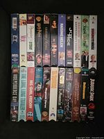 Two rows of VHS spines including E.T., Bicentennial Man, Legends of the Fall, The Mummy, Raising Helen, You’ve Got Mail, Independence Day, The Long Good Friday, His Girl Friday, Jurassic Park and others.