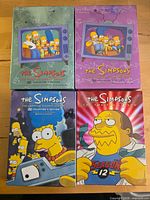 Front view of four sealed The Simpsons DVD box sets seasons 2,3,7,12