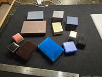 All 12 boxes arranged on black surface with ruler for scale