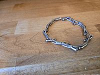 Full view of articulated metal sleeve garter in oval form