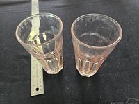 Two pink Depression glass tumblers side by side with ruler for scale
