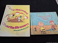 Front covers of both books: A Boy Named Charlie Brown (yellow cover) and You're In Love, Charlie Brown (blue-green cover)