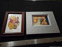 Both framed pictures side by side with ruler for scale