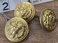 Front view of three gold-tone Navy buttons showing eagle and anchor insignia