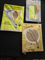 Three sealed packages of vintage stockings and tights on black background