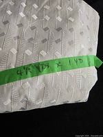folded white jacquard fabric labeled 4½ yds x 1 yd