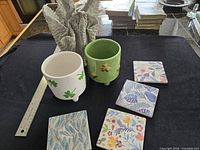 Overview of three planters and four decorative tiles with ruler for scale