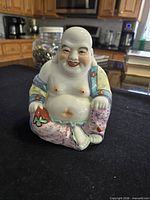 Front view of seated multicolored porcelain Laughing Buddha figurine