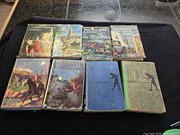 Front view showing all 8 mystery books, four with illustrated dust jackets and four without