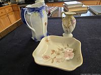 Three ceramic pieces displayed: flow blue jug, small floral vase, square floral dish