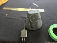 Front view of speaker showing Qi pad, phone rest slot, attached power cable and wall adapter