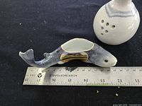 Glazed fish dish beside ruler and perforated bud vase