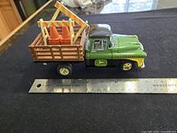Full view of truck beside ruler showing size, stake sides, traffic cones, barricade