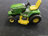 Left side view of John Deere X485 toy tractor showing body, seat and mower deck