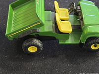 Left side view showing tilting cargo bed, yellow seats, wheel detail