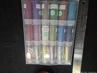 Front view of sealed 18-vial glitter set with ruler for scale