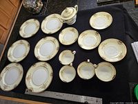 All sixteen Noritake Goldier pieces displayed on black cloth