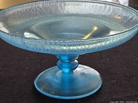 Side view of blue iridescent crackle glass pedestal compote dish