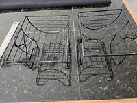 Two black wire baskets side-by-side showing size and shape